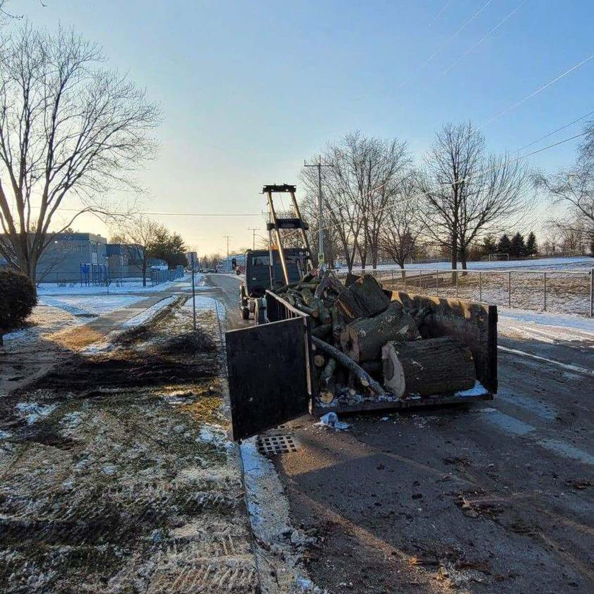 Crane lifting a log section at a winter job site